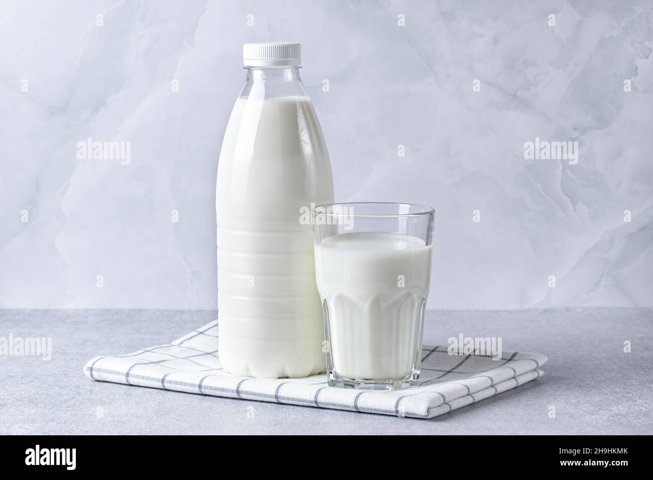 Bottiglia e bicchiere di latte su un tavolo grigio. Fondo alimentare, ingrediente di cottura, bevanda. Cibo sano, una fonte di calcio Foto Stock
