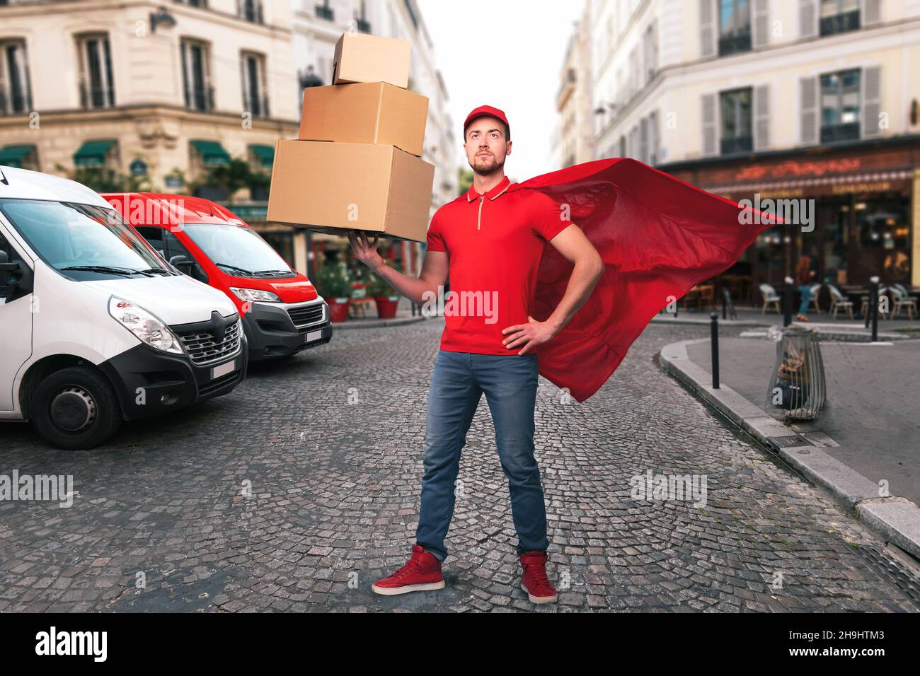 Uomo supereroe con uniforme rossa davanti ai negozi per la consegna e il ritiro della merce Foto Stock