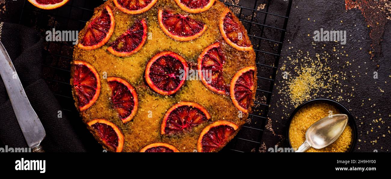 Torta arancione di sangue capovolta su vecchio sfondo di cemento scuro. Stile rustico. Messa a fuoco selettiva Foto Stock