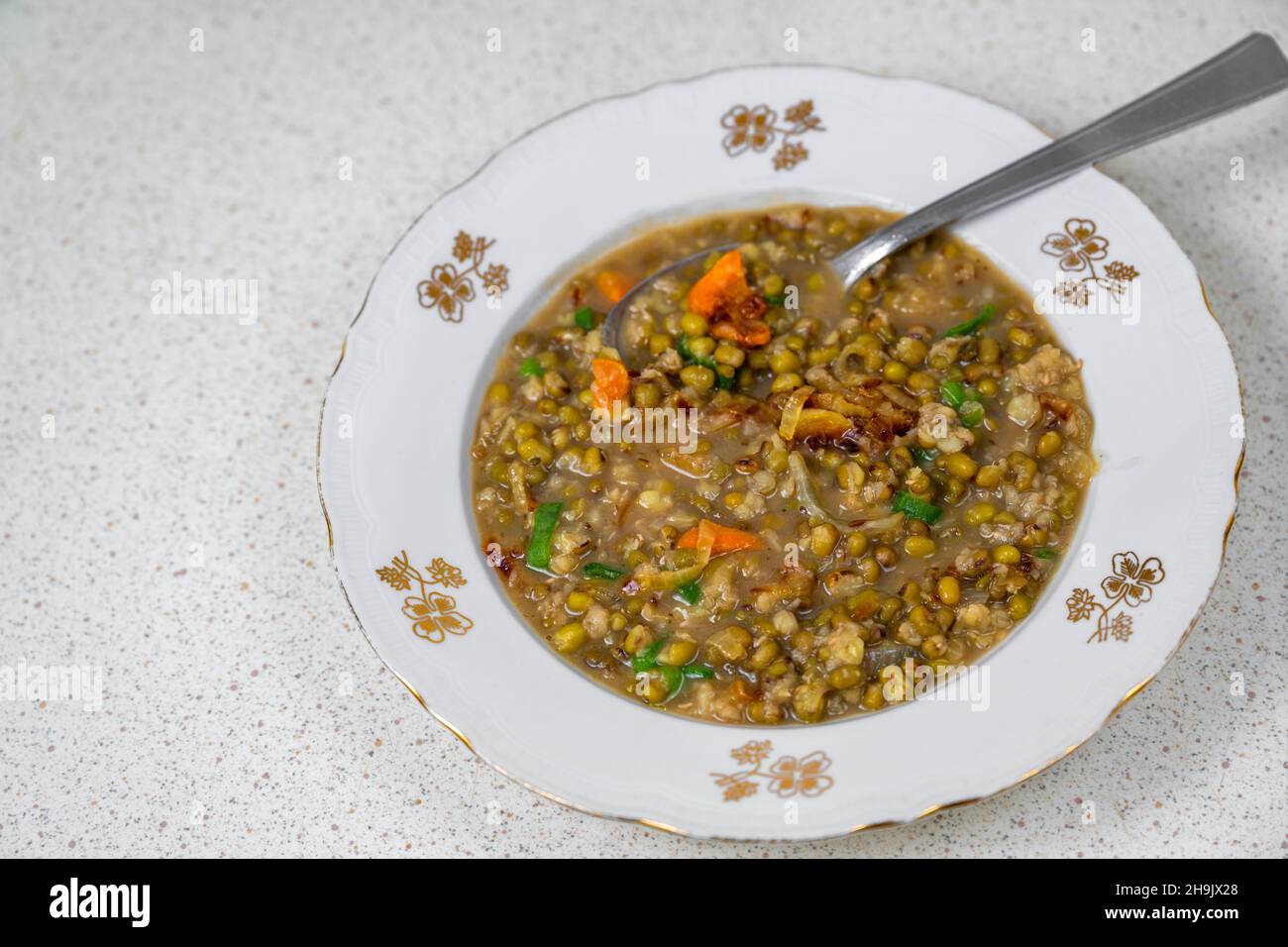 Zuppa di fagioli Mungo (vigna radiata) in piatto con cucchiaio (vigna radiata) sul tavolo. Cibo vegetariano o vegano. Foto Stock