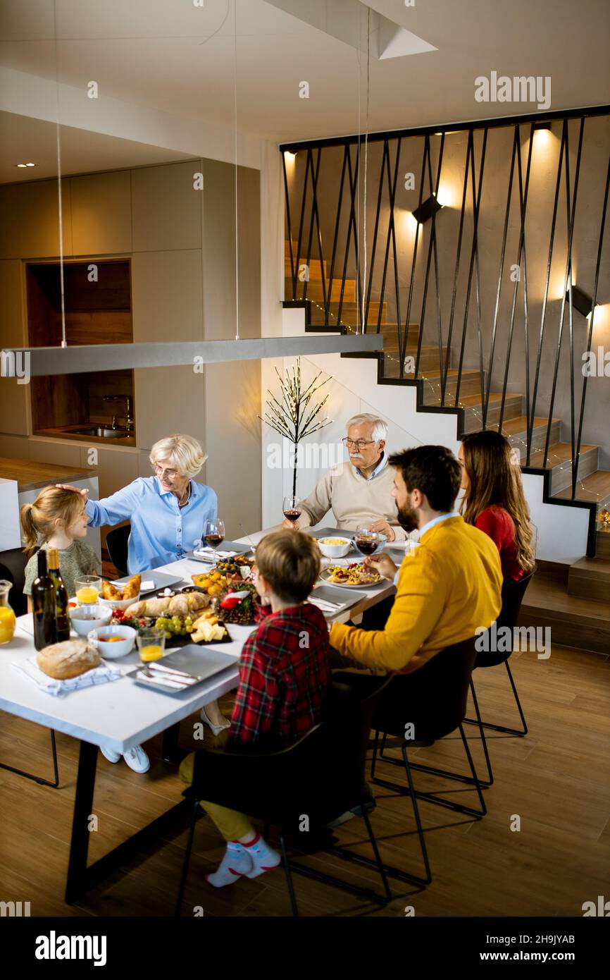 Famiglia felice che ha una cena con vino rosso a casa Foto Stock