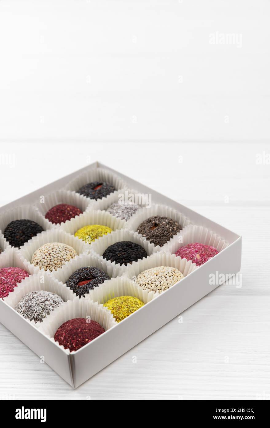 Scatola di dolci vegani palle energetiche su tavolo di legno bianco. Foto Stock