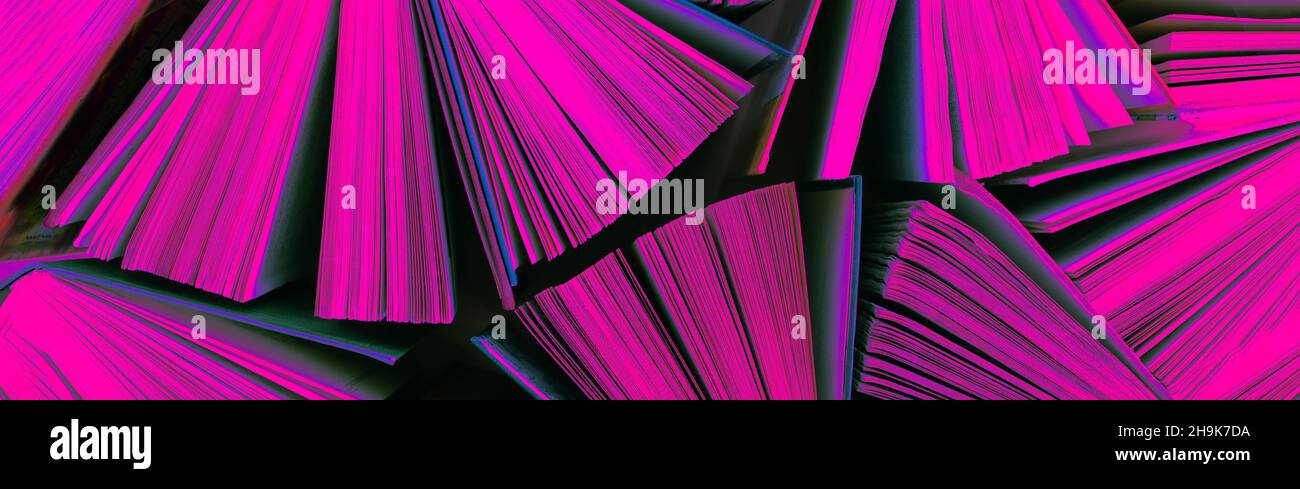 Molti stack di libri colorati in luce al neon. Vecchi libri hardback come sfondo. Torna a scuola. Foto Stock