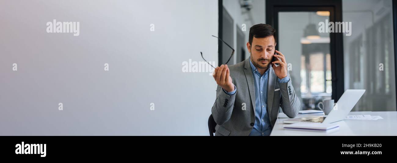 Banner panorama di stressato fuori fastidioso uomo d'affari in ufficio facendo importante telefonata su un problema serio che funziona sotto pressione e stretto d Foto Stock