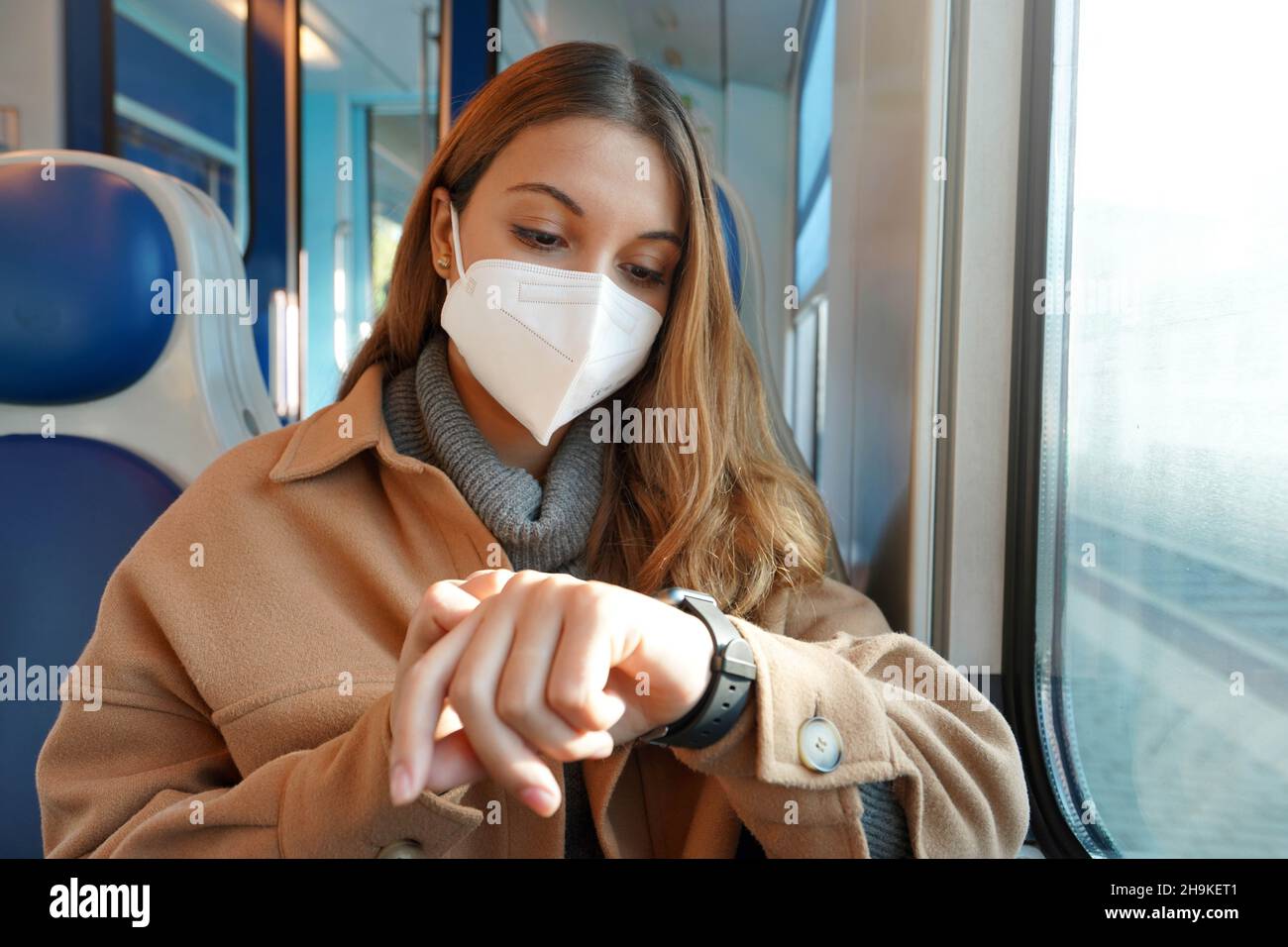 Trasporto pubblico in ritardo. Donna d'affari sul treno che guarda lo smartwatch mentre il suo treno è fermato sulla ferrovia nel mezzo del nulla. Persone e la d Foto Stock