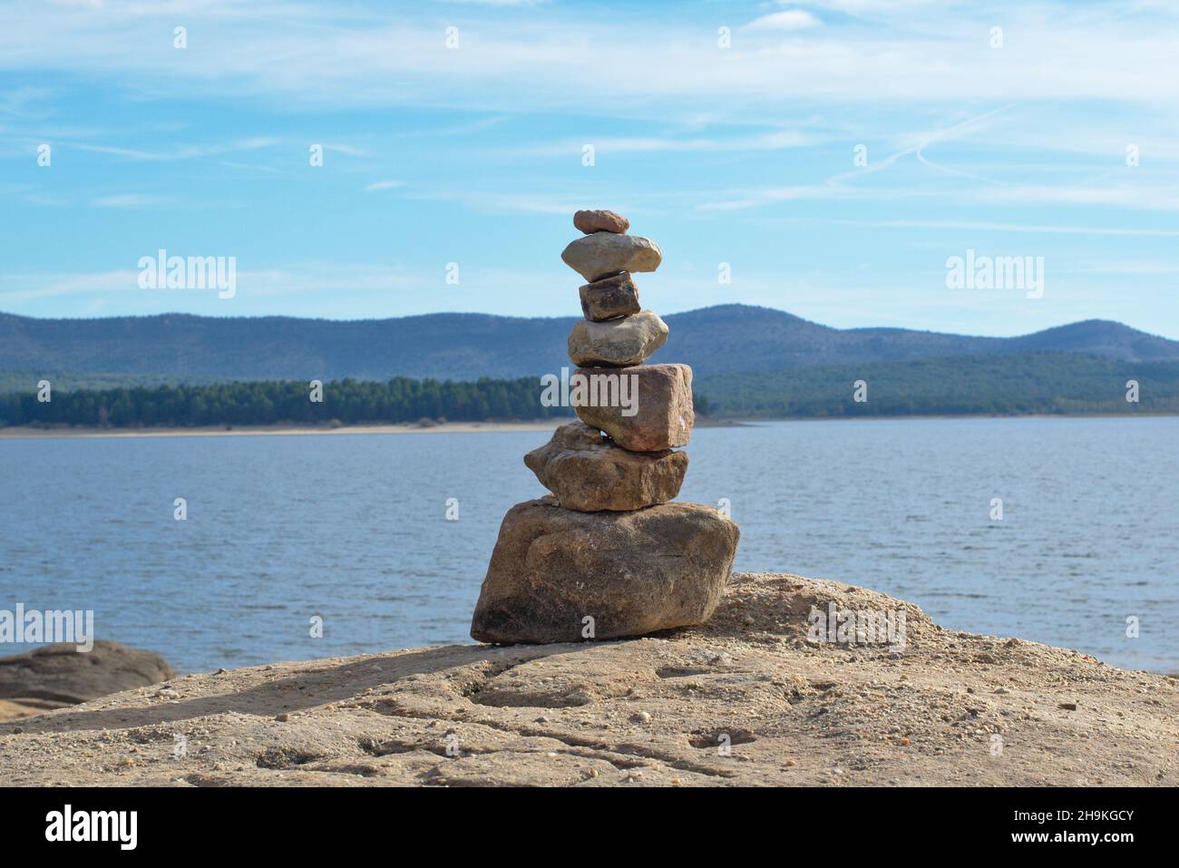 Mucchio di pietre accatastate dal lago. Simbolo di bilanciamento interno. Lago e montagna con pini sullo sfondo. Foto Stock