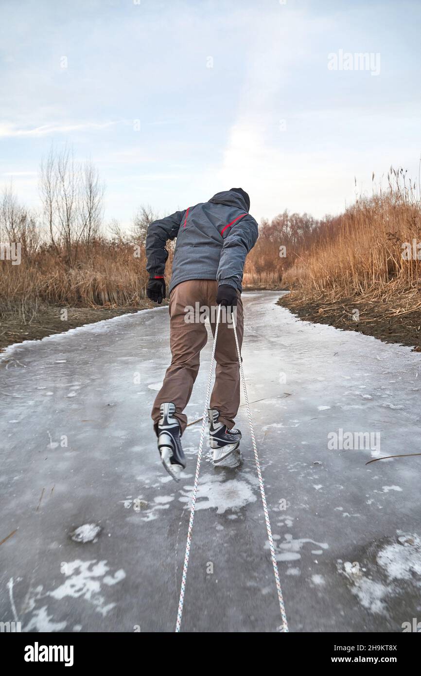 Uomo pattinaggio su ghiaccio che tira la slitta su ghiaccio Foto Stock