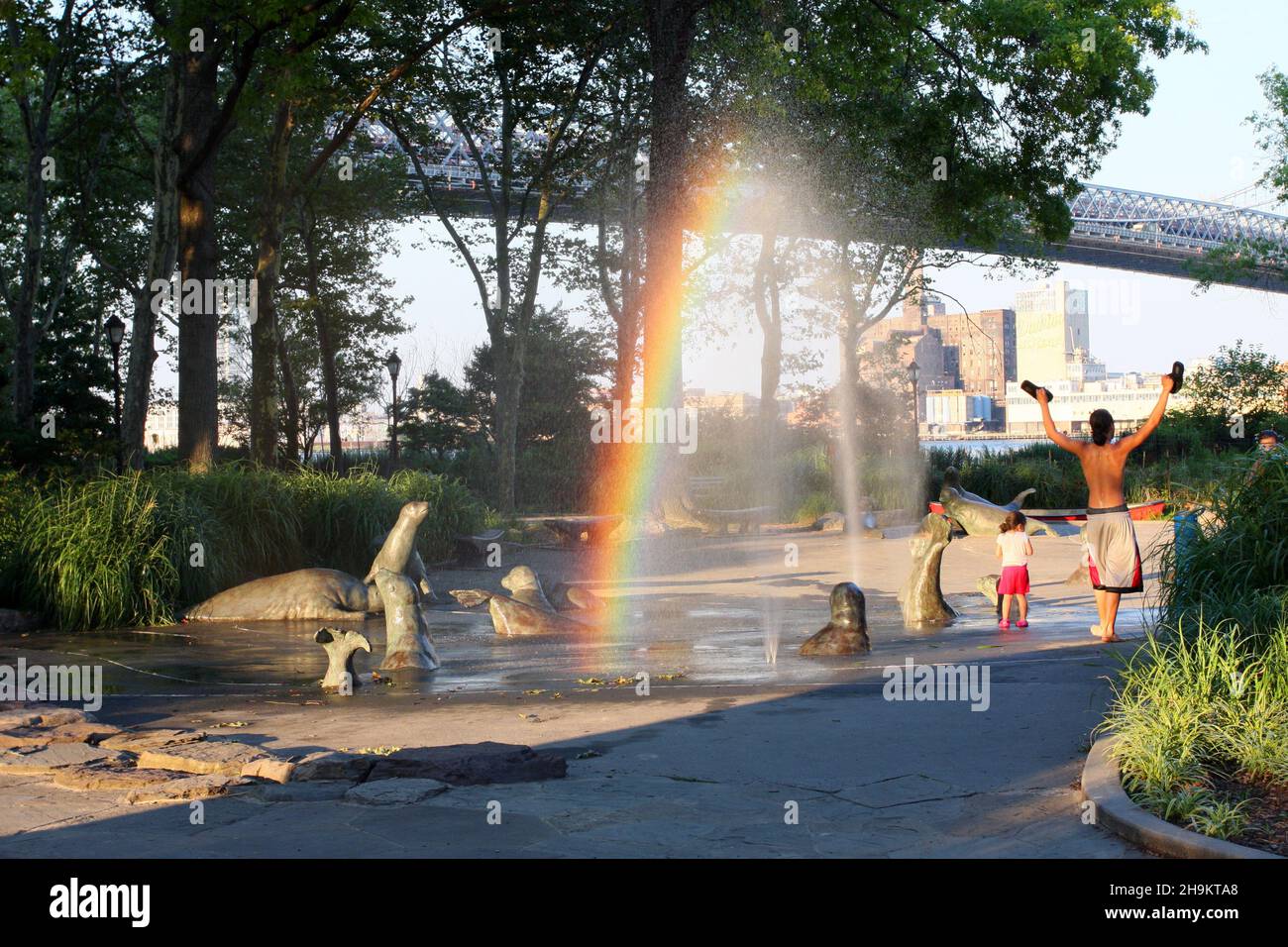 Le persone che si godono la guarnizione del porto spruzzi docce con arcobaleno bonus a East River Park durante un caldo pomeriggio estivo, New York, NY. Luglio 2015 Foto Stock