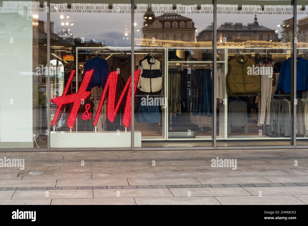 HM negozio di abbigliamento al dettaglio, ingresso al negozio con persone, gente sul marciapiede di strada, finestre e vestiti in mostra, HM Europe Foto Stock