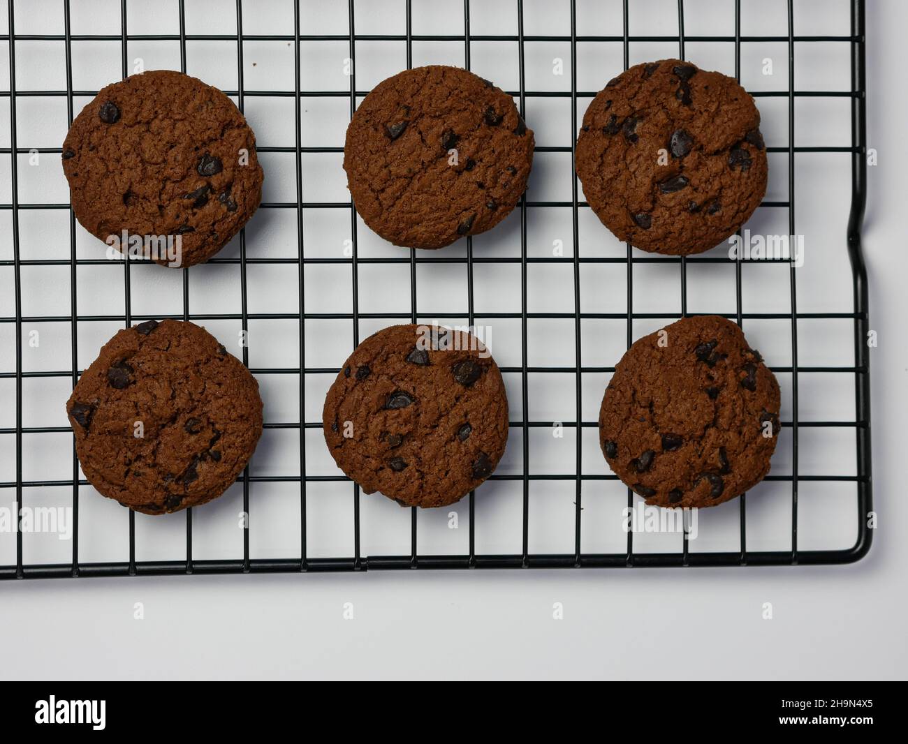 biscotti con scaglie di cioccolato su griglia di raffreddamento con sfondo bianco. Buongiorno, piatto, vista dall'alto Foto Stock