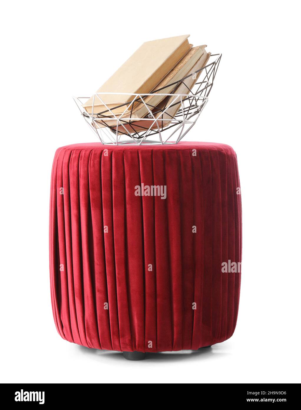 Pouf rosso con cesti e libri su sfondo bianco Foto Stock