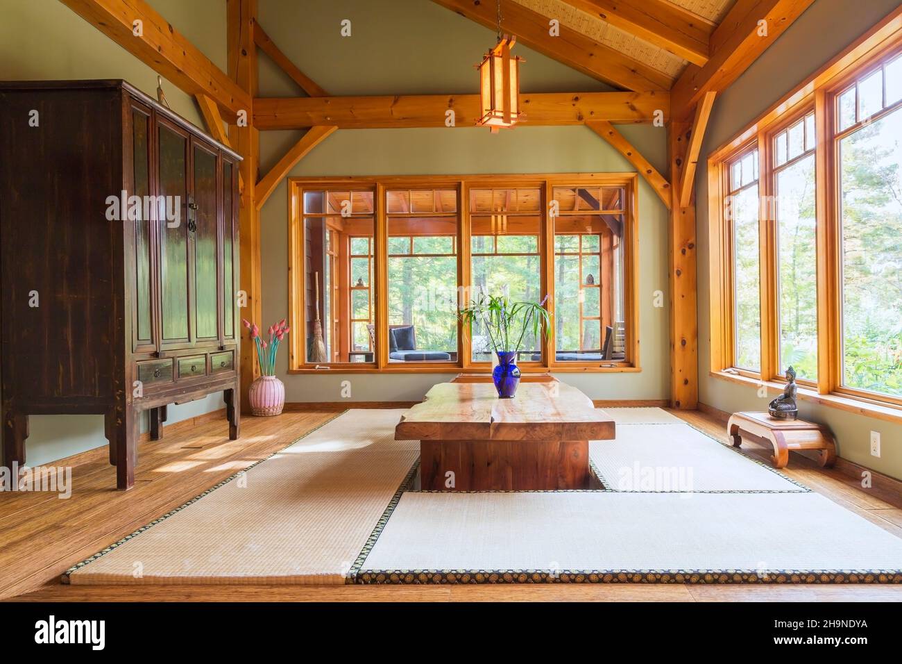 Tavolo da pranzo in legno rustico verniciato con tappetini in tatami, armoire cinese nero e marrone, piccoli tavoli in legno di teak indonesiano nella sala da pranzo in stile giapponese Foto Stock