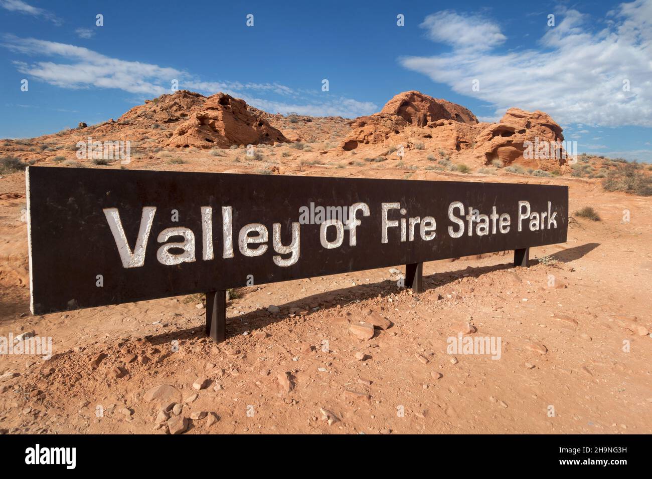 Ingresso al Valley of Fire state Park in Nevada, USA con cartello da tavolo con lettere bianche e paesaggio scenico di Desert Rock sullo sfondo Foto Stock