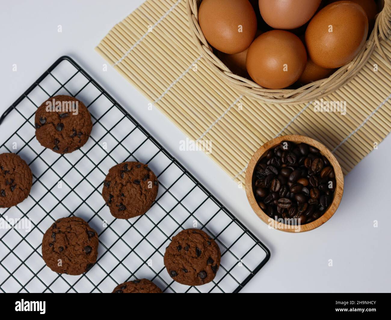 biscotti con pezzetti di cioccolato sulla griglia di raffreddamento con chicchi di caffè in ciotola di bambù e cestino per uova Foto Stock