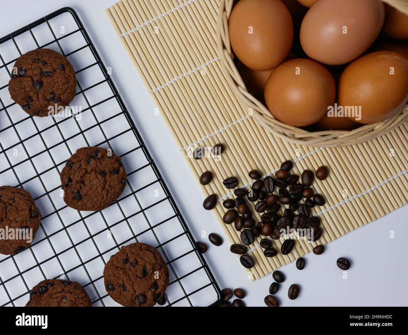 biscotti con pezzetti di cioccolato sulla griglia di raffreddamento con chicchi di caffè sparsi e cestino per uova Foto Stock