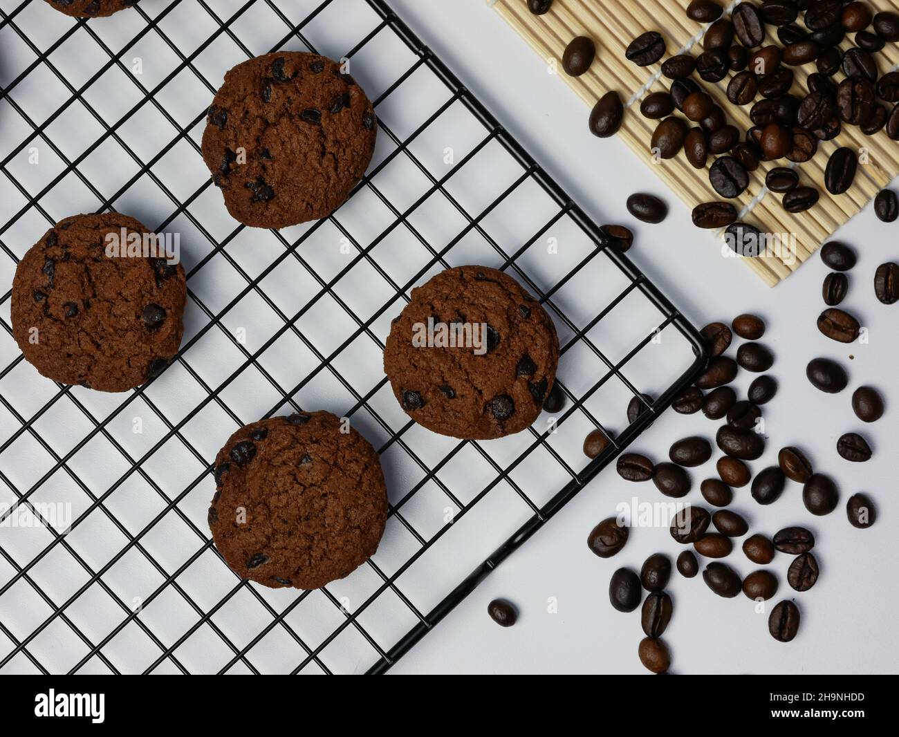 biscotti con gocce di cioccolato su una griglia di raffreddamento con chicchi di caffè sparsi Foto Stock