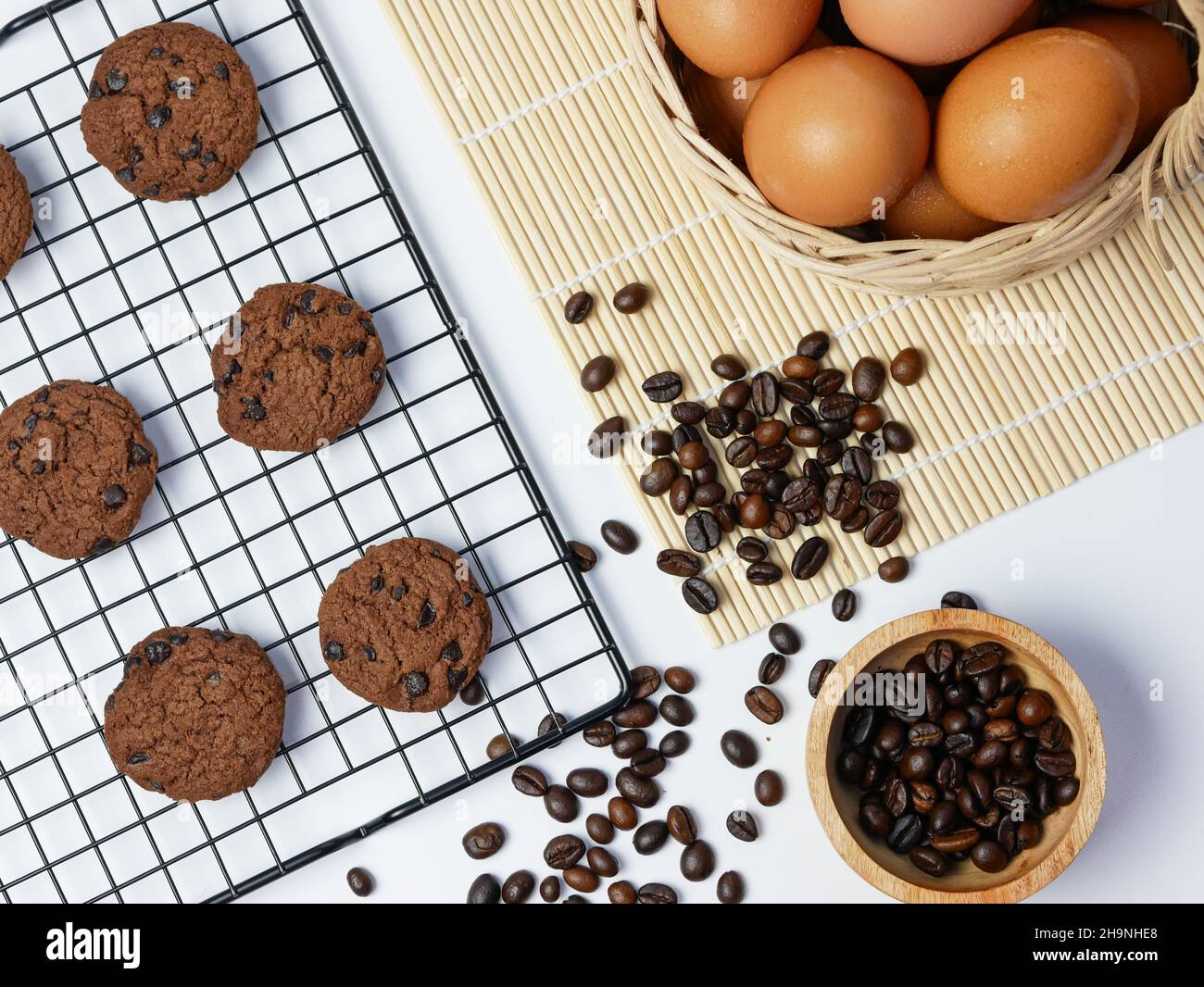 biscotti con pezzetti di cioccolato sulla griglia di raffreddamento con chicchi di caffè in ciotola di bambù e cestino per uova Foto Stock