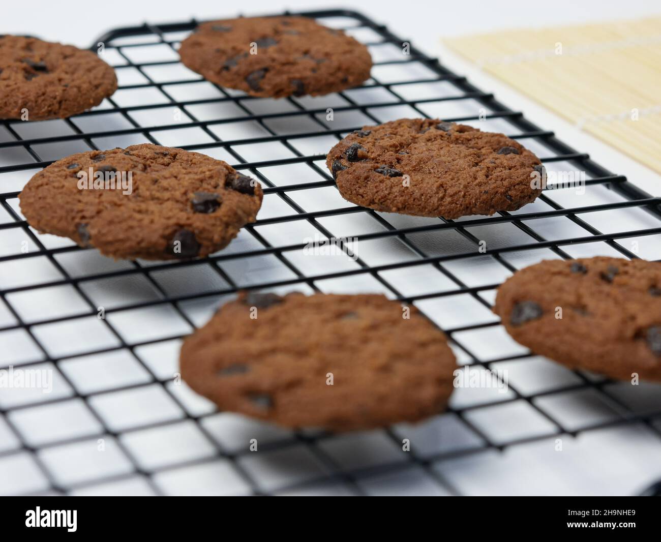 biscotti con gocce di cioccolato su griglia di raffreddamento su sfondo bianco Foto Stock