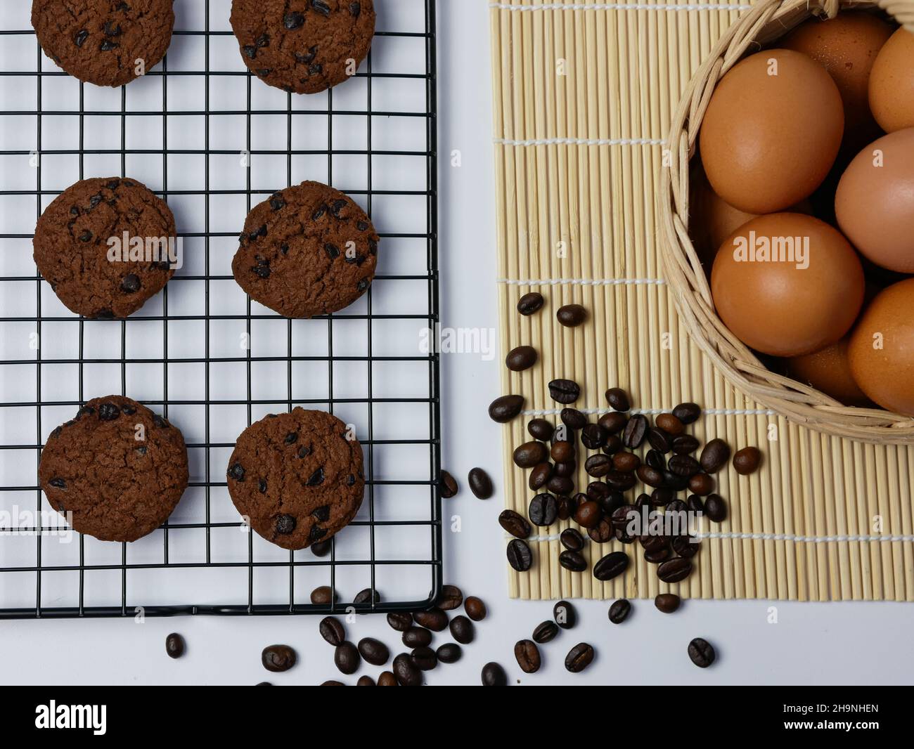 biscotti con pezzetti di cioccolato sulla griglia di raffreddamento con chicchi di caffè sparsi e cestino per uova Foto Stock