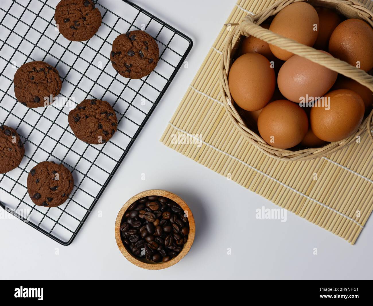 biscotti con pezzetti di cioccolato sulla griglia di raffreddamento con chicchi di caffè in ciotola di bambù e cestino per uova Foto Stock