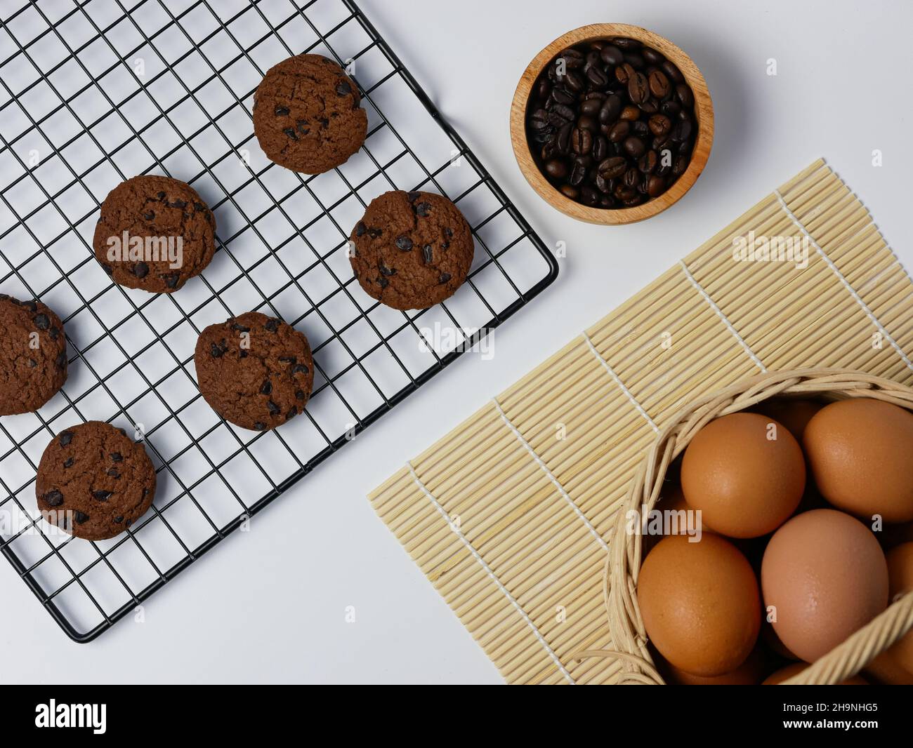 biscotti con pezzetti di cioccolato sulla griglia di raffreddamento con chicchi di caffè in ciotola di bambù e cestino per uova Foto Stock
