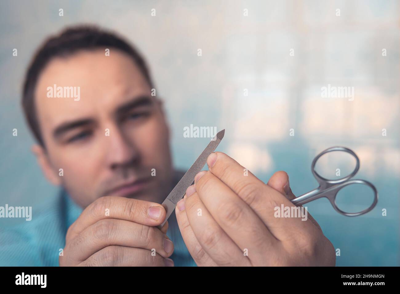 Le dita e le unghie dell'uomo durante il manicure. Segatura unghie con lima unghie, primo piano Foto Stock