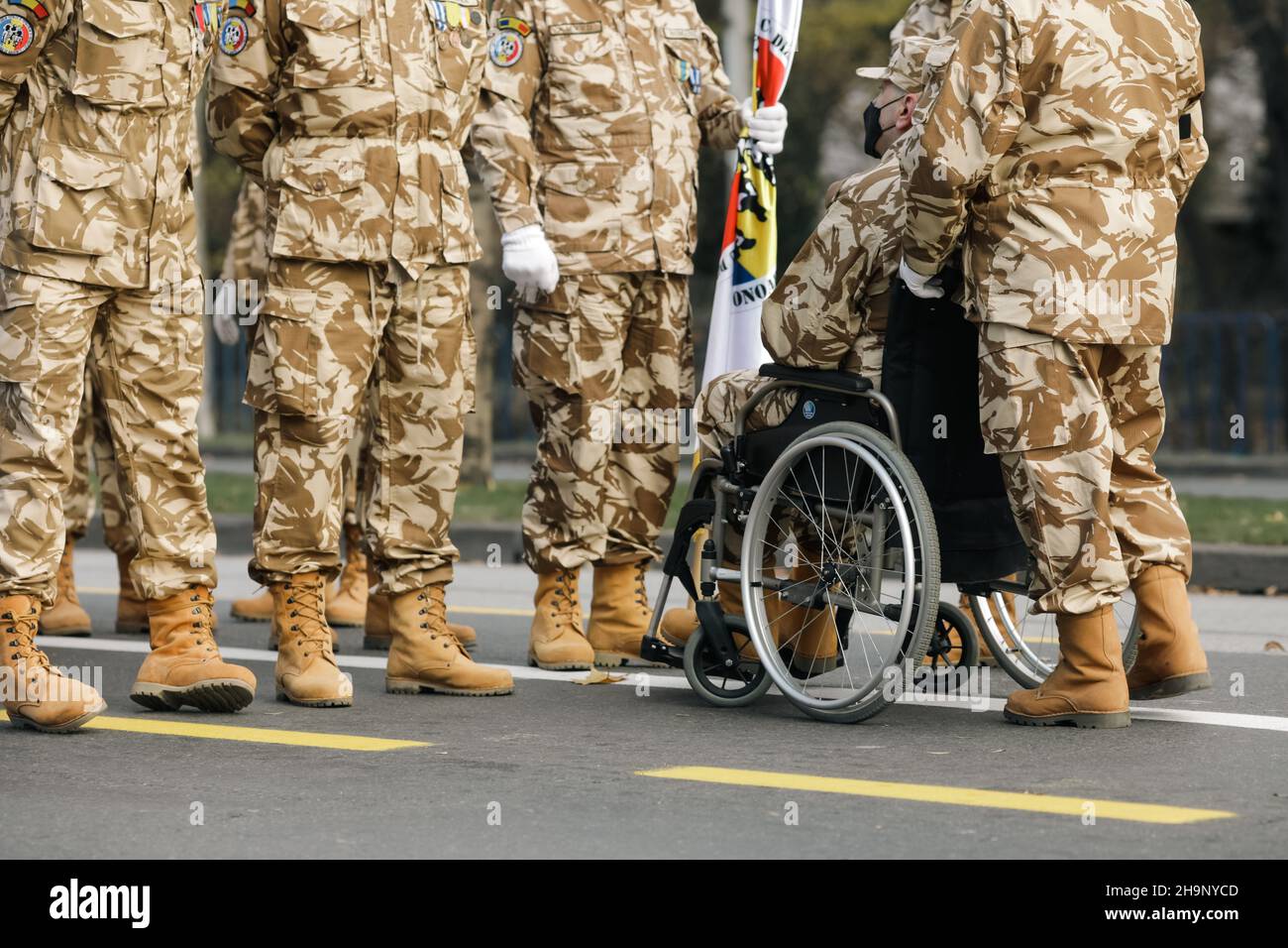 Bucarest, Romania - 1 dicembre 2021: Soldati veterani dell'esercito rumeno, di cui uno è ferito e disabile, seduti su una sedia a rotelle. Foto Stock