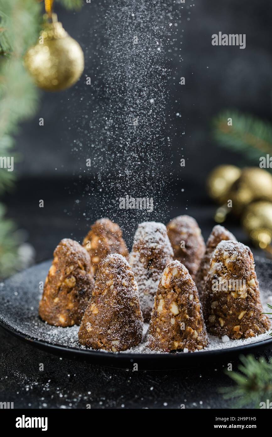 Delizioso senza cottura cioccolato dessert di Natale energia sana pino  cono, cosparso di zucchero in polvere. Decorata con rami di abete. Vegan  des sano Foto stock - Alamy