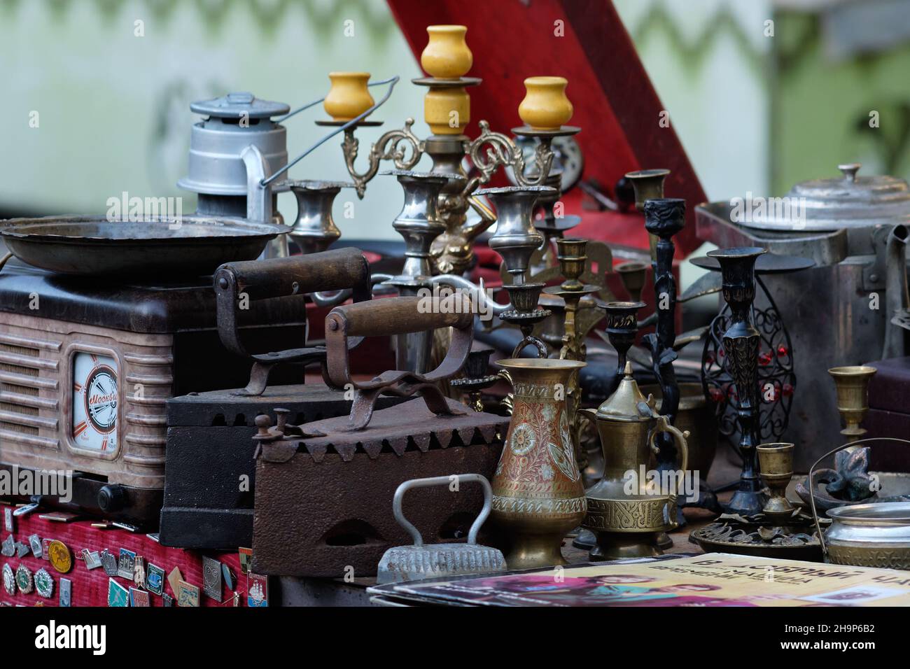 Mercato vintage che espone una vecchia radio sovietica, antichi ferri al carbone, portacandeli, vasi di ottone, dischi in vinile, ordini sovietici ecc. Foto Stock