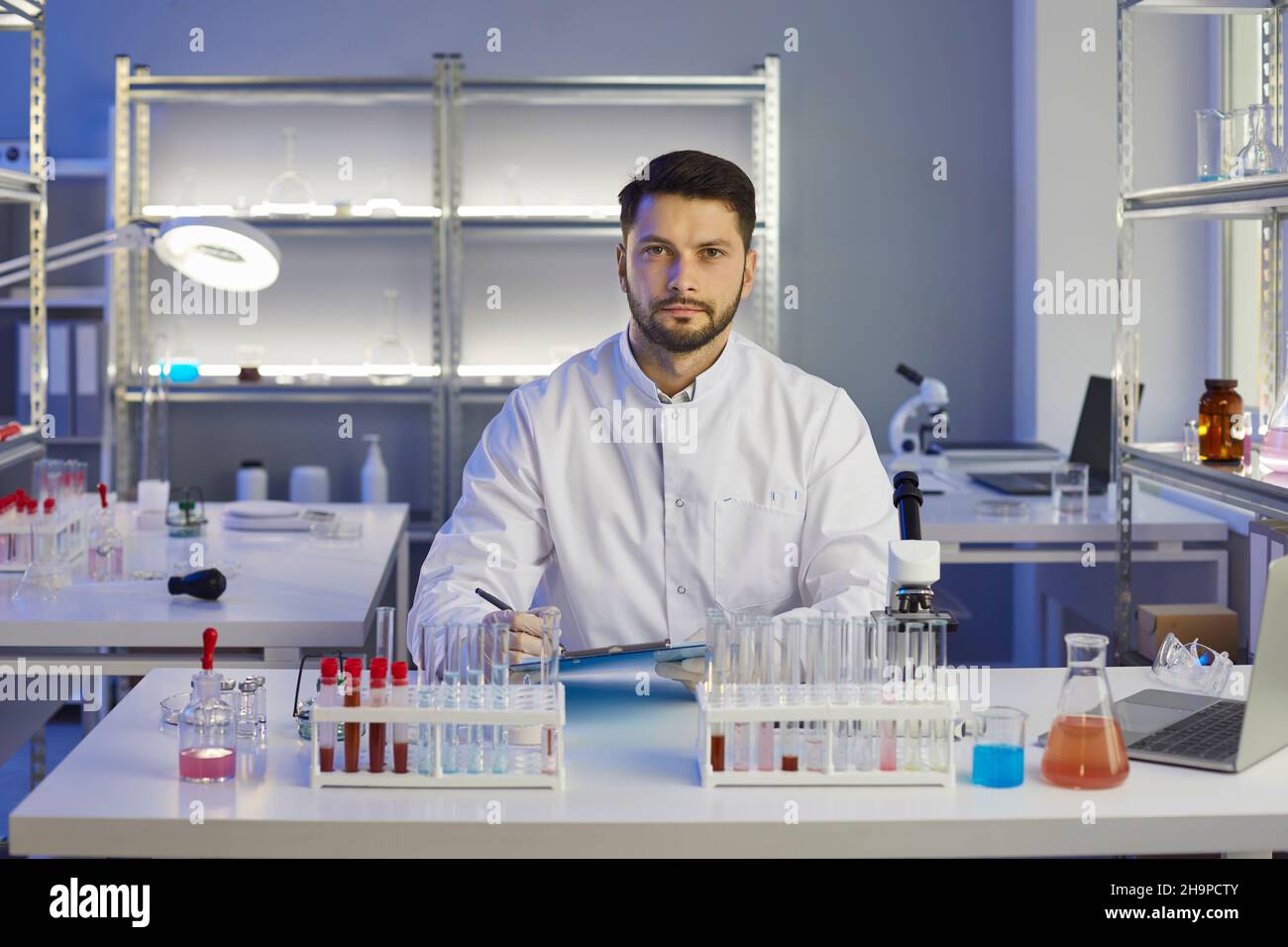 Ritratto di un serio scienziato maschile che prende appunti mentre si lavora su un nuovo farmaco in un laboratorio. Foto Stock