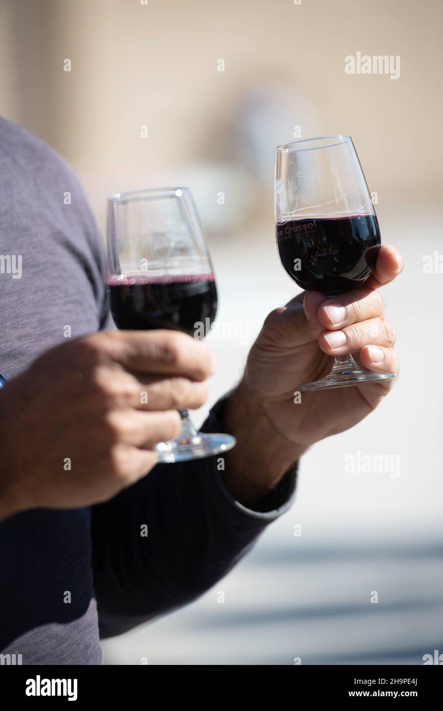 Uomo con un bicchiere di vino in ogni mano durante una bottega “Apero sur un plateau, vins & fromages” (degustazione di vino e formaggio) ad Alboussiere (sud-pasqua Foto Stock