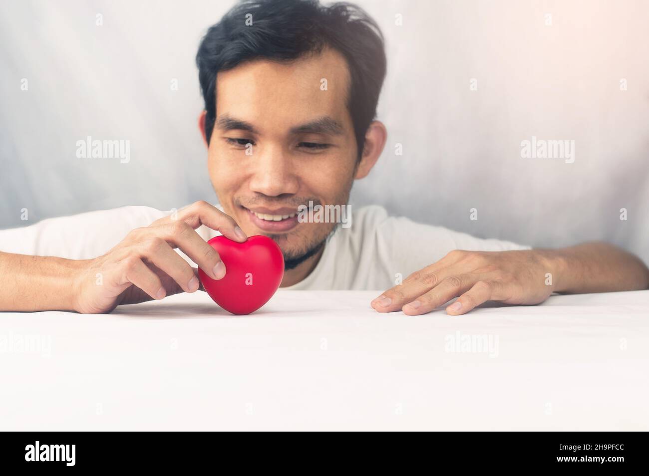 L'uomo felice che tiene il cuore rosso, il giorno del cuore del mondo, il cuore rosso Foto Stock