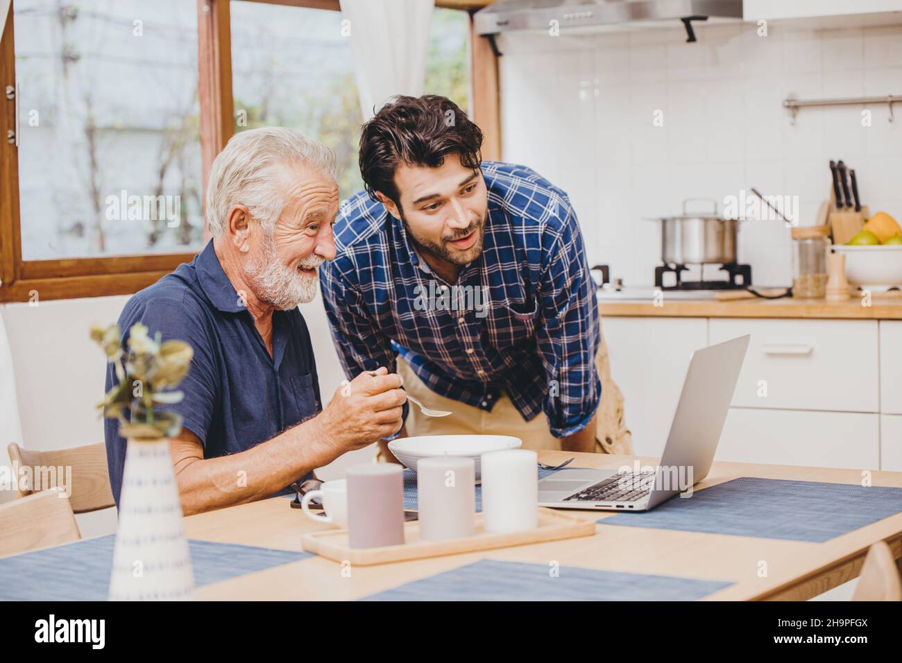 giovane uomo con anziano sano godere di utilizzare il computer online per guardare e parlare su internet videochiamata riunione con nipote durante soggiorno a casa Foto Stock
