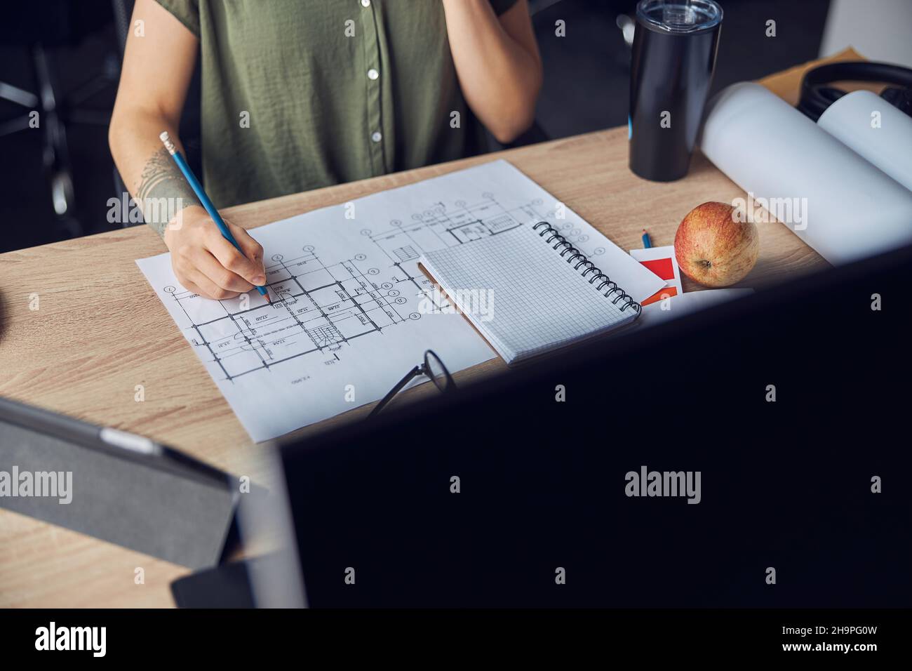 Primo piano di mano di interior designer femminile che fa appunti su un progetto, seduto al tavolo nel suo ufficio Foto Stock