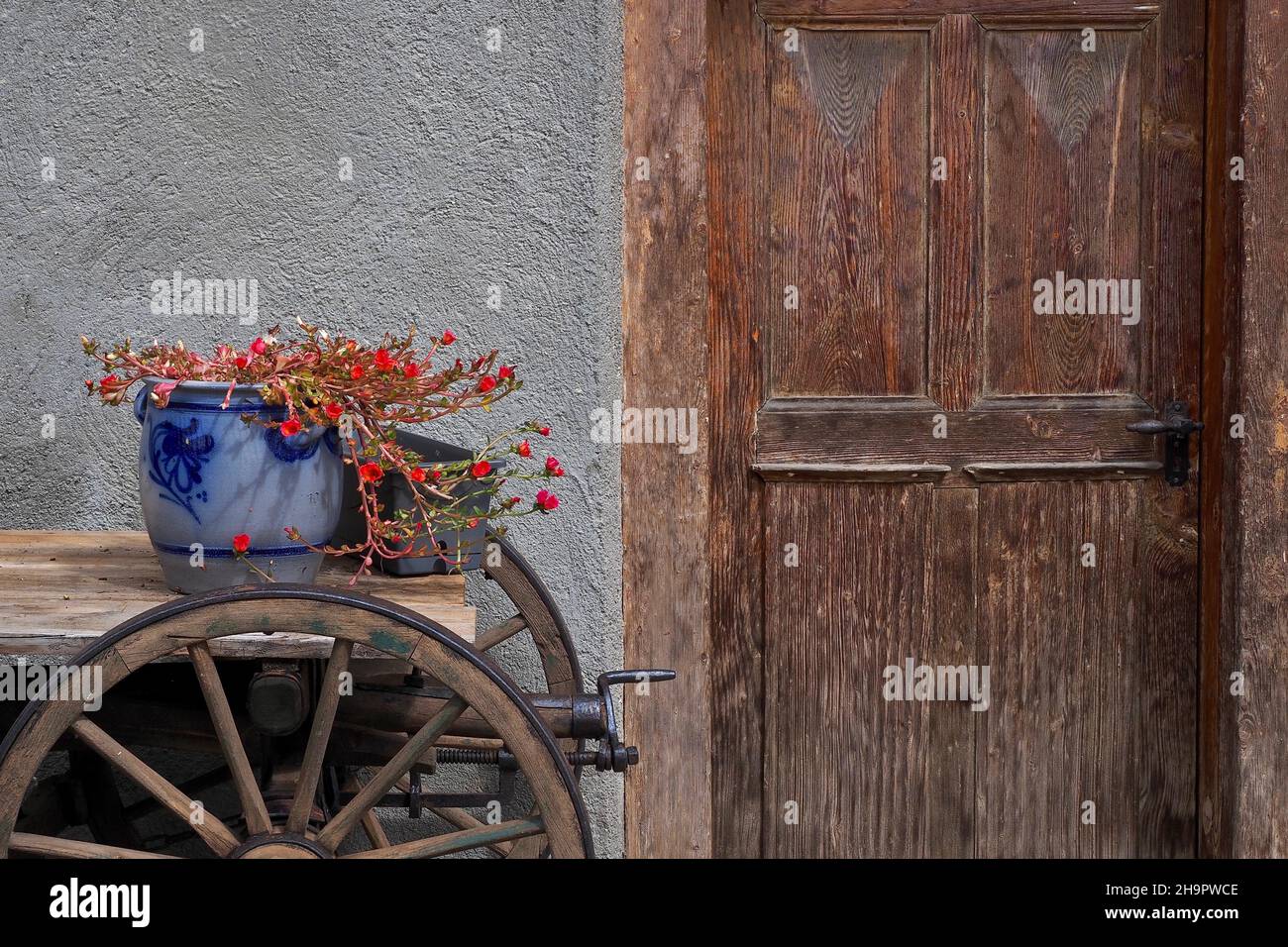 Ancora vita con vaso di argilla e carro di legno davanti a porta di legno, ruote di legno, ruote di carro, Trin, Svizzera Foto Stock