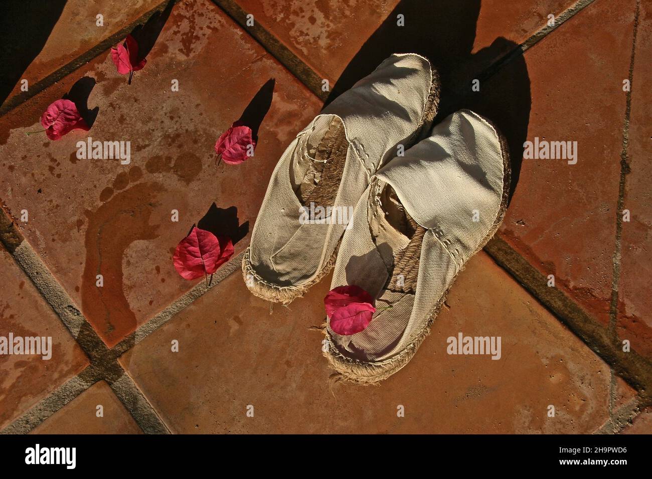 Footprint umido accanto a espandrillos, scarpe nazionali spagnole, scarpe casual, loafer, pantofole, scarpe comode, scarpe in tela, palle in tessuto, naturale Foto Stock