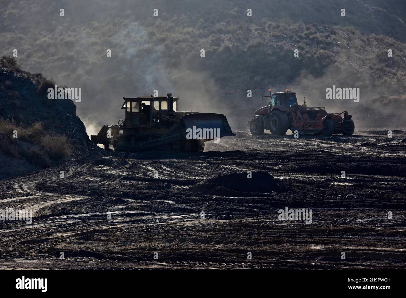 Bulldozer che spingono pianeggiante terreno collinare, movimento terra, bonifica del terreno, lavori di campo, costruzione di strade, trattori livellamento campi, coltivazione di ortaggi Foto Stock