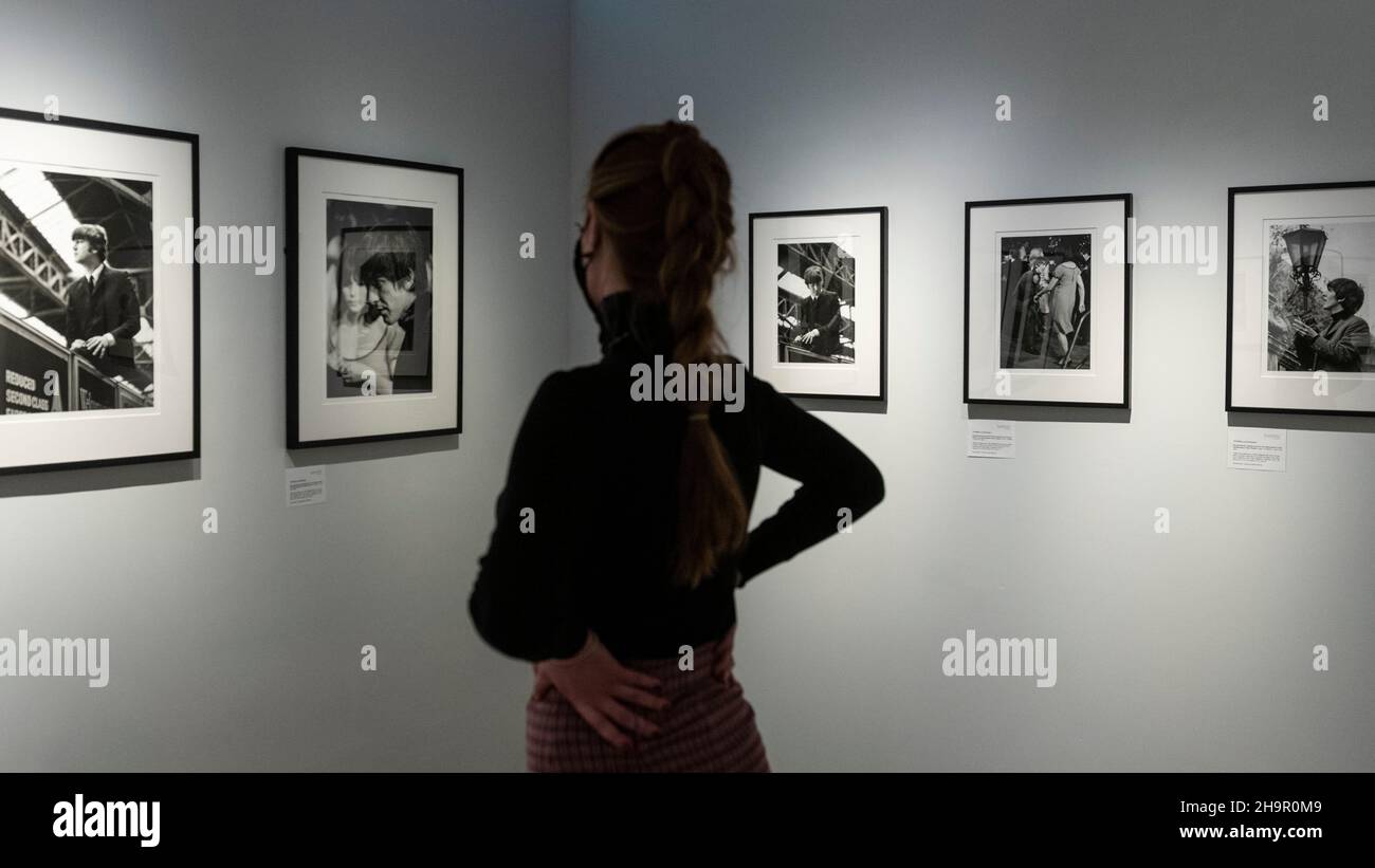 Londra, Regno Unito. 8 dicembre 2021. Un membro dello staff guarda le foto in anteprima di una mostra di fotografie perse dei Beatles di Lord Thynne, figlio della marchessa di Bath del 6th. La mostra, con immagini candide della band nella primavera del 1964 sul set del loro primo film A Hard Day’s Night, si trova alla Shapero Modern Gallery di Mayfair fino al 16 gennaio 2022. Credit: Stephen Chung / Alamy Live News Foto Stock