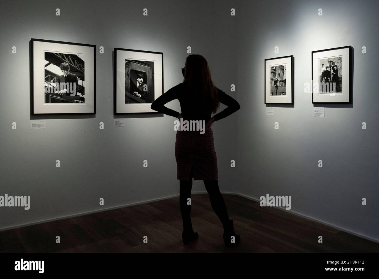 Londra, Regno Unito. 8 dicembre 2021. Un membro dello staff guarda le foto in anteprima di una mostra di fotografie perse dei Beatles di Lord Thynne, figlio della marchessa di Bath del 6th. La mostra, con immagini candide della band nella primavera del 1964 sul set del loro primo film A Hard Day’s Night, si trova alla Shapero Modern Gallery di Mayfair fino al 16 gennaio 2022. Credit: Stephen Chung / Alamy Live News Foto Stock