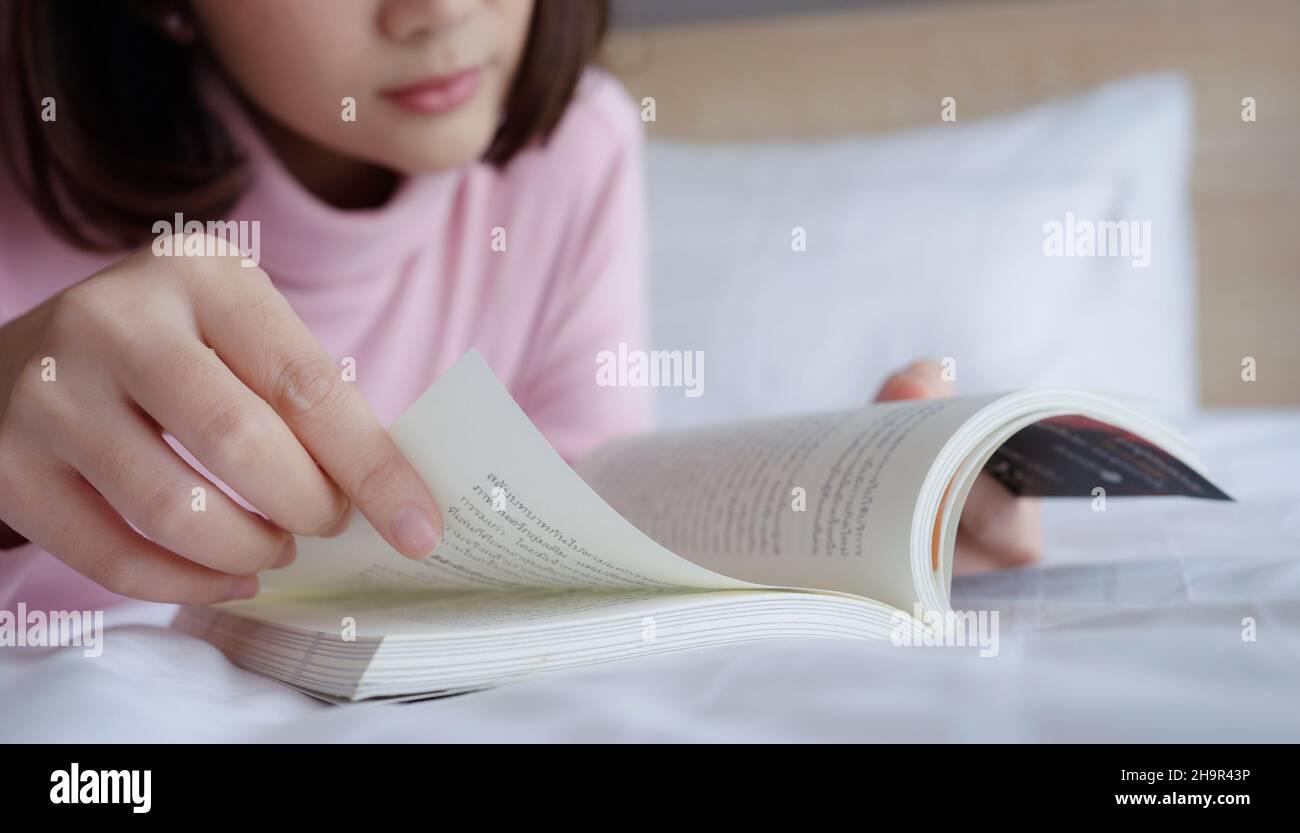 Giovane donna sdraiata e letto libro a letto. Foto Stock