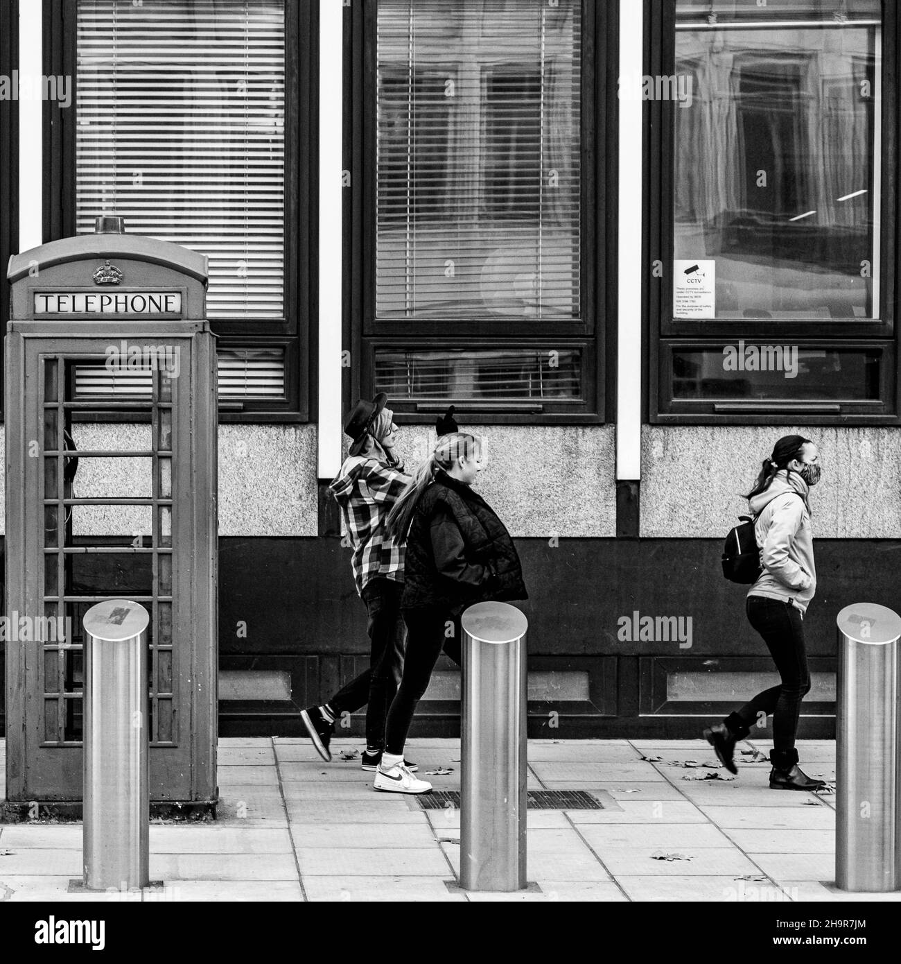 Centro di Londra UK Novembre 21 2021, tre donne che camminano oltre il telefono pubblico a pagamento Box Victoria Street Londra Foto Stock