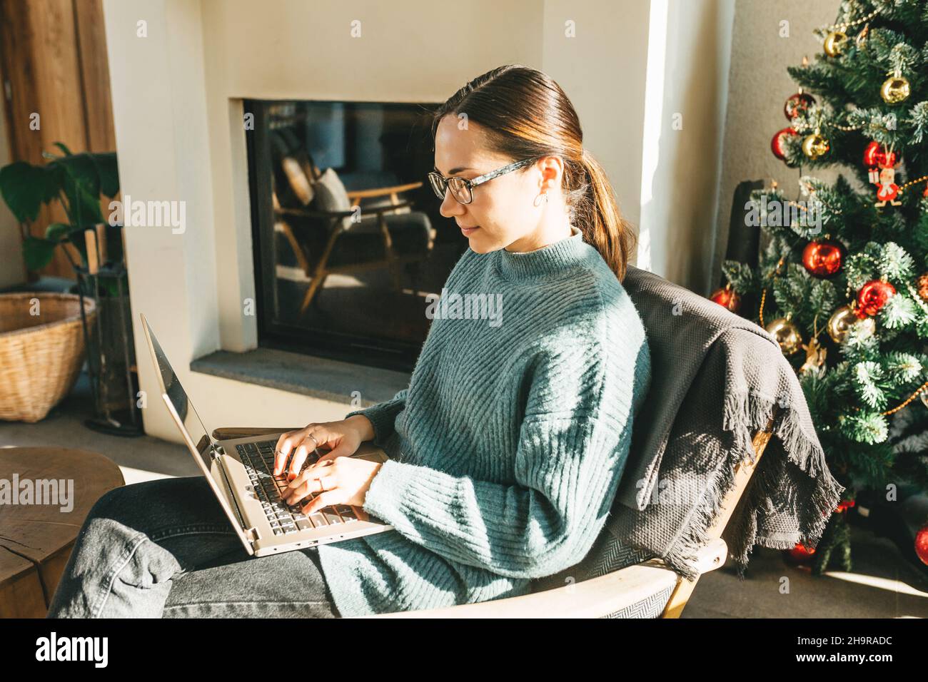 Lavoro a casa, videoconferenza, videochiamata per riunioni online, riunioni virtuali, apprendimento a distanza. Una donna d'affari in abiti casual conduce una videochiamata, si impegna in e-mail, comunica online con i colleghi, invia e risponde alle e-mail, sviluppa software mentre si siede a casa sul divano. Una donna intelligente lavora da remoto. Foto Stock