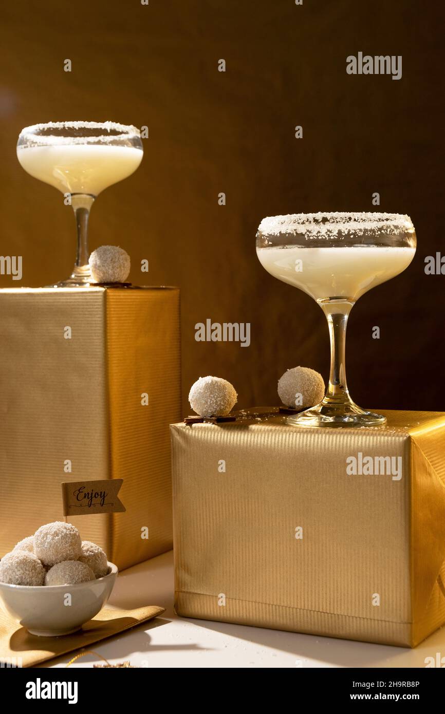 Bevande festive. Bicchieri bianchi da cocktail in cocco su sfondo dorato. Concetto di celebrazione Foto Stock