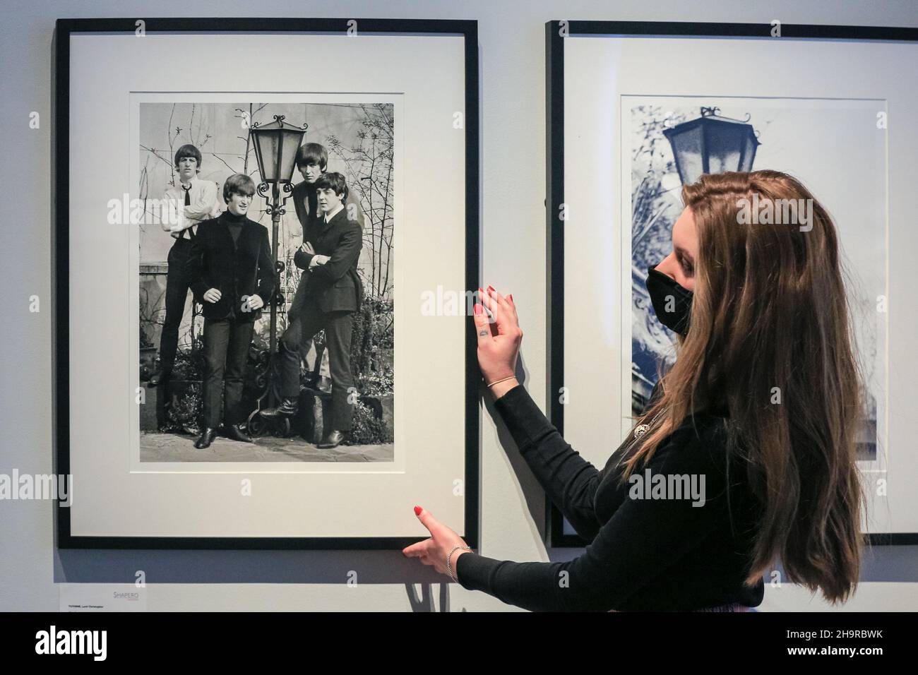 Londra, Regno Unito. 8th Dic 2021. Un membro dello staff guarda le foto, qui una rara foto di gruppo. Riscoperta in documenti di famiglia dopo 57 anni e sviluppata da negativi, le fotografie perse dei Beatles sono viste in una rara mostra alla Galleria moderna di Shapero. Il fotografo, Lord Thynne, ha catturato candidi colpi della band nella primavera del 1964, sul set del loro primo film A Hard Day's Night. I negativi sono rimasti insviluppati per cinquantasette anni. Credit: Imagplotter/Alamy Live News Foto Stock