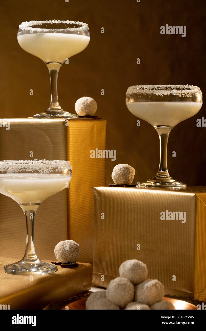 Bevande festive. Bicchieri bianchi da cocktail in cocco su sfondo dorato. Concetto di celebrazione Foto Stock