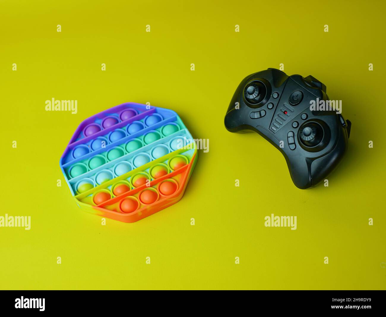 Black game pad e Rainbow Pop it fidget giocattolo su uno sfondo vuoto spazio copia Foto Stock
