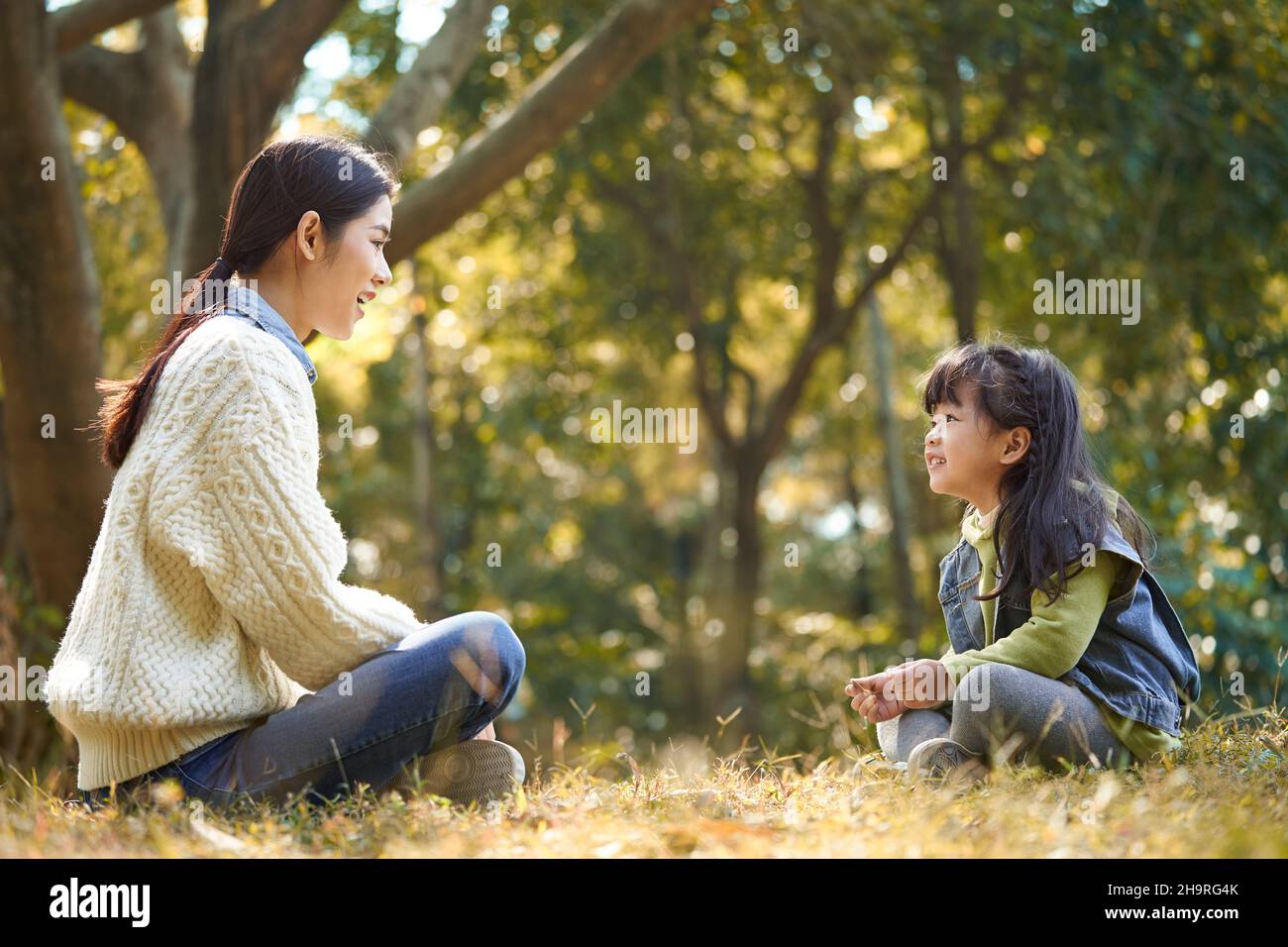 giovane madre asiatica e figlia che si godono una conversazione all'aperto nel parco della città Foto Stock