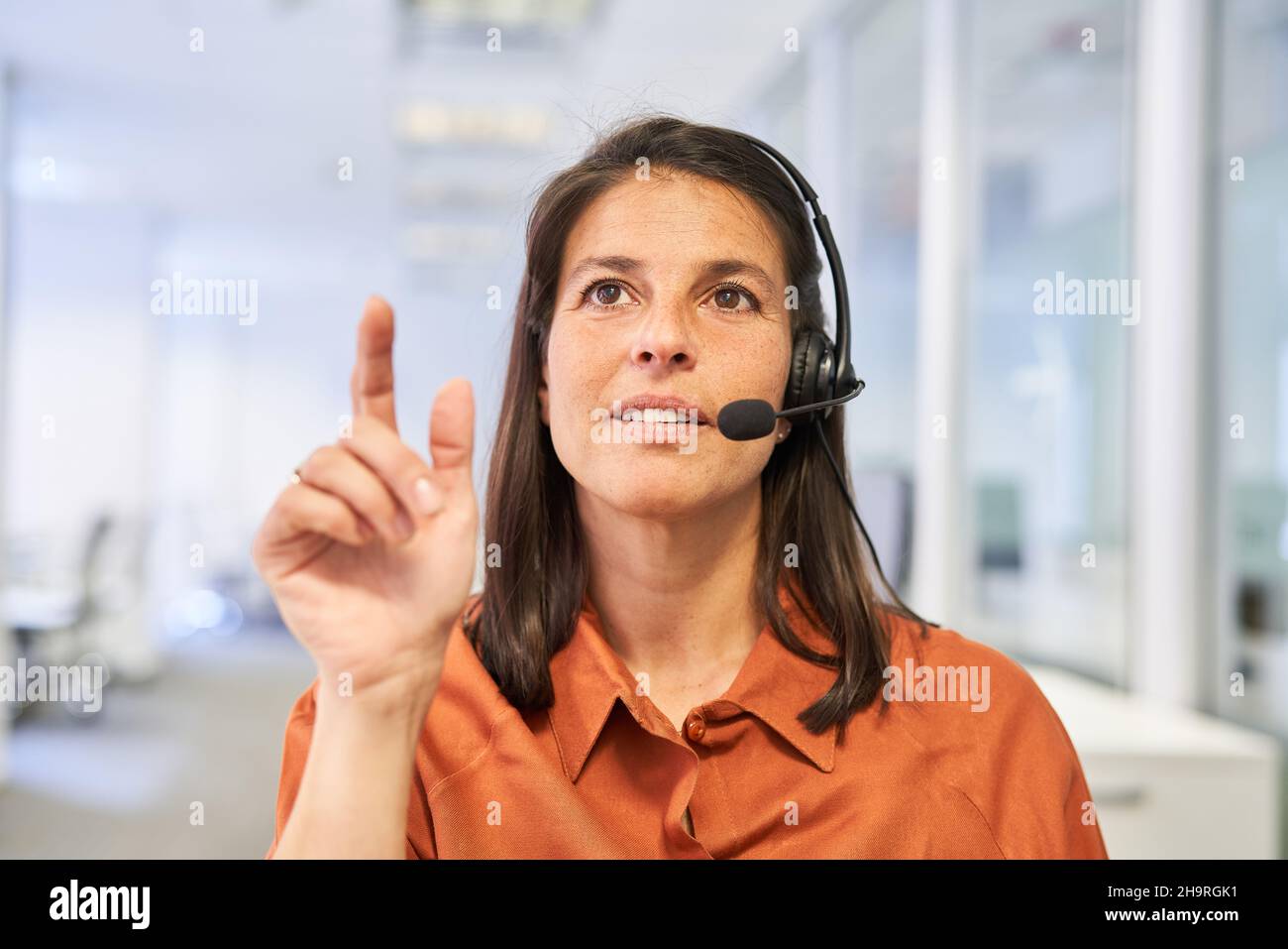 Donna d'affari in qualità di operatore e rappresentante del servizio clienti con cuffie durante la chat video Foto Stock