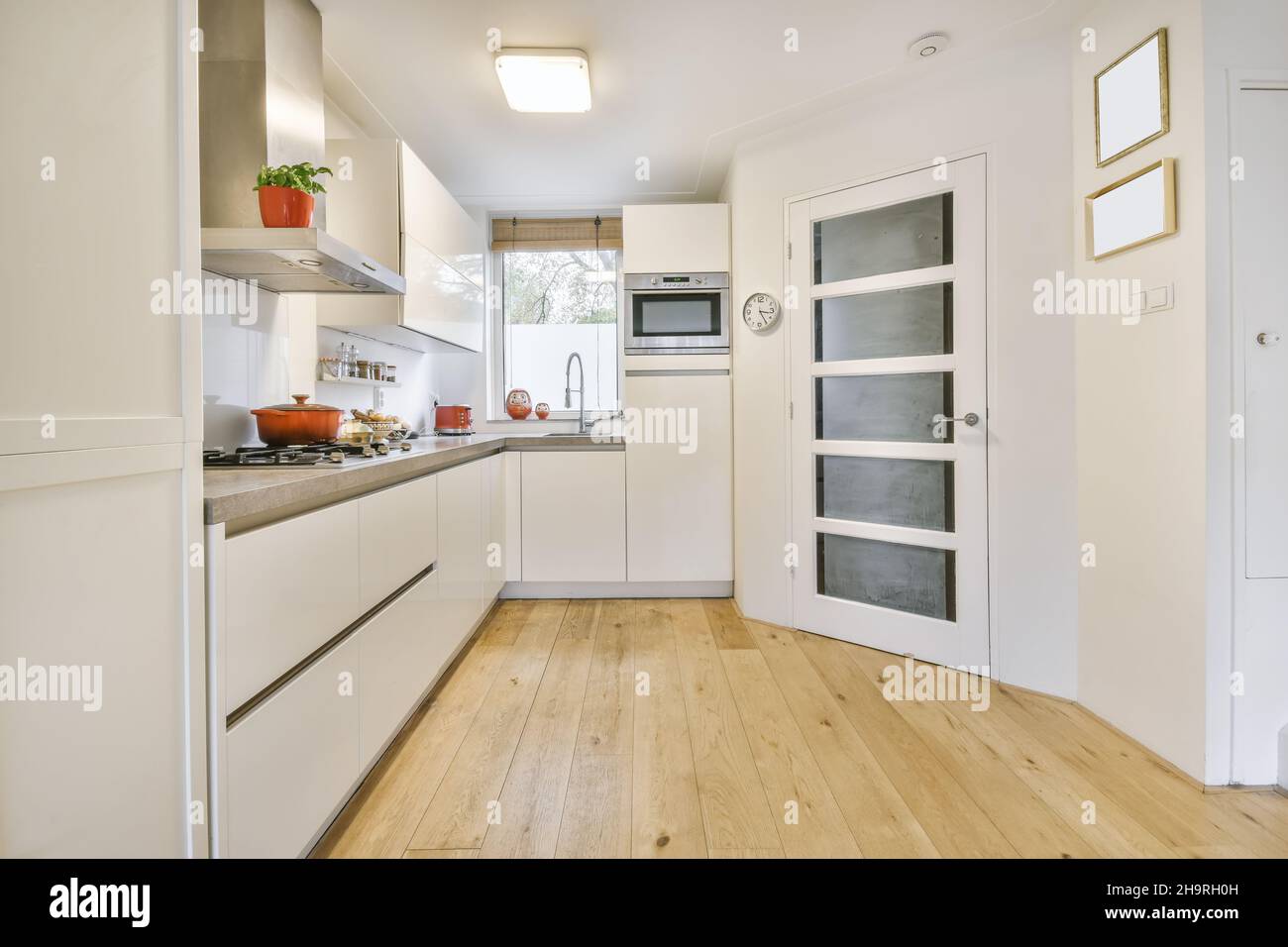 Accogliente cucina con mobili bianchi e pavimenti in legno Foto Stock