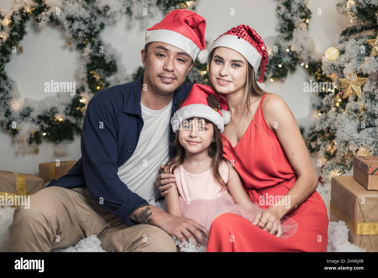 Foto di famiglia studio di Natale. Foto di Capodanno di famiglia felice misto con figlia carina. Tre persone in rosso cappelli di Natale. Tenerezza di Natale Foto Stock